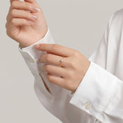 Hands at a white shirt cuff with a gold solitaire ring