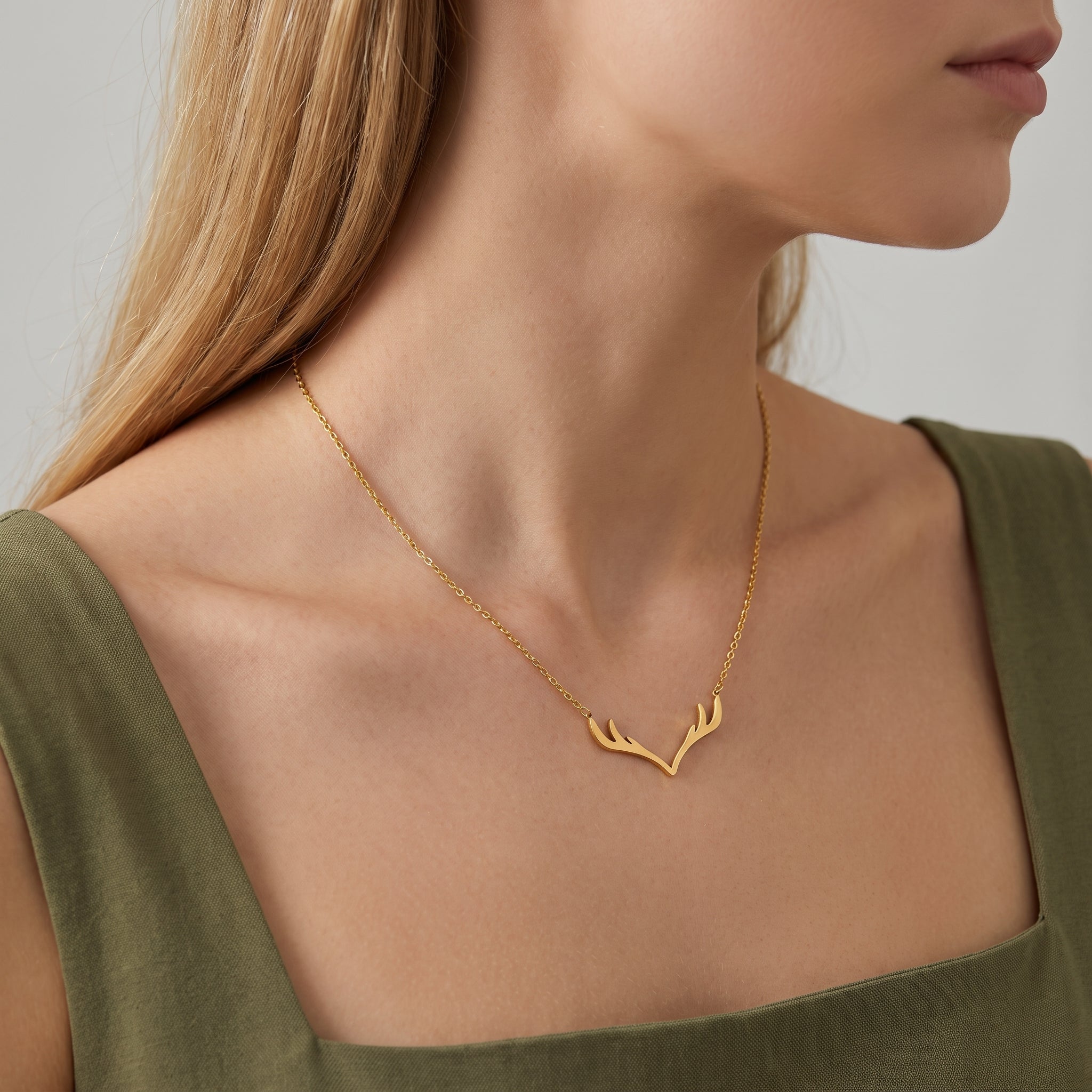 Gold antler necklace on a cable chain, worn at the collarbone