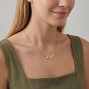Gold antler necklace worn with a relaxed smile, olive green dress