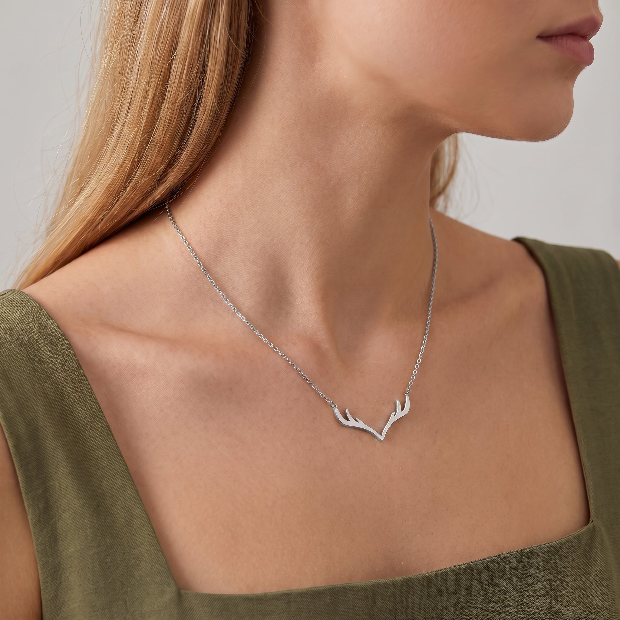 Silver antler necklace on a cable chain, worn at the collarbone