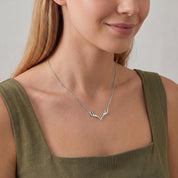 Silver antler necklace worn with a relaxed smile, olive green dress