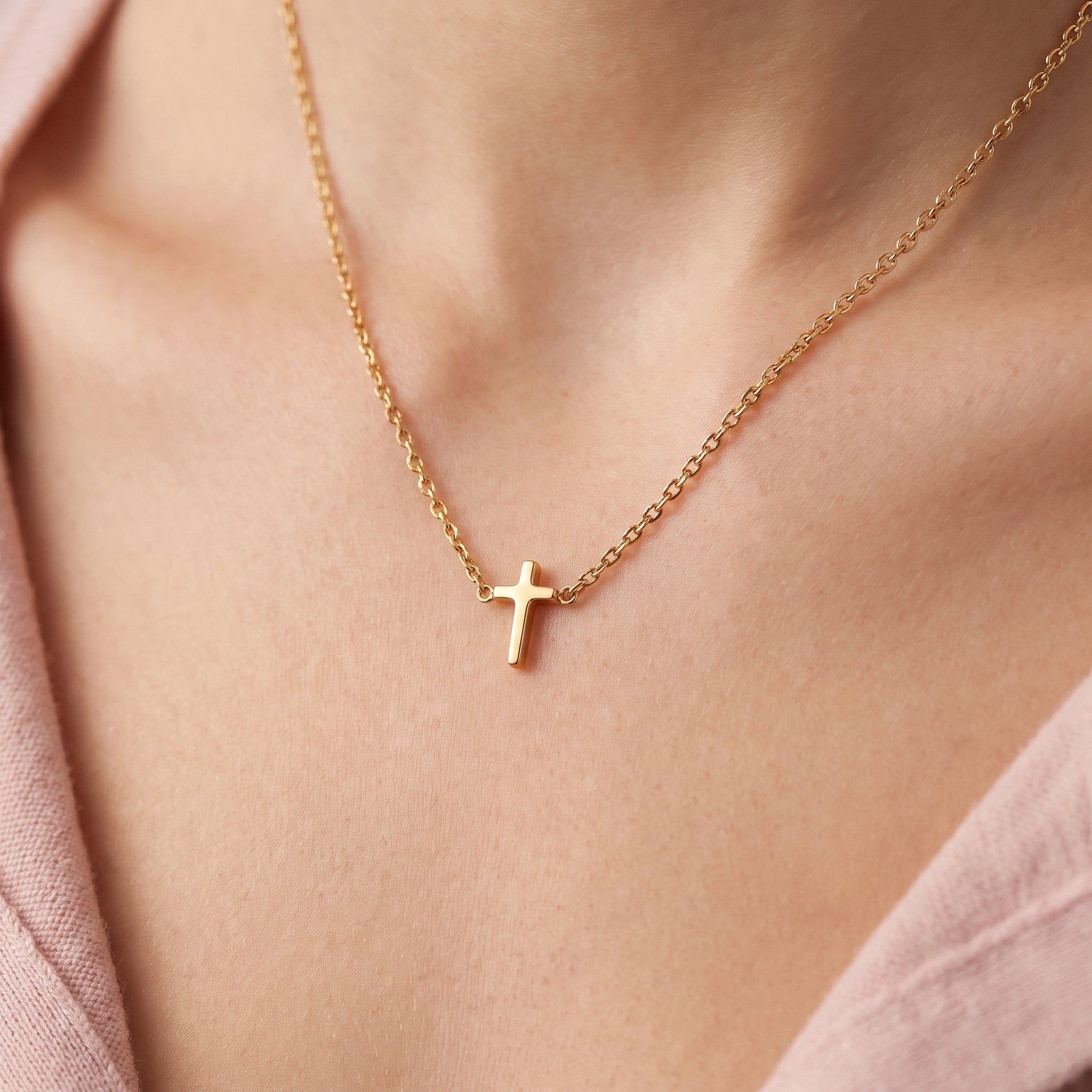 Gold tiny cross necklace, close-up of the polished cross on skin