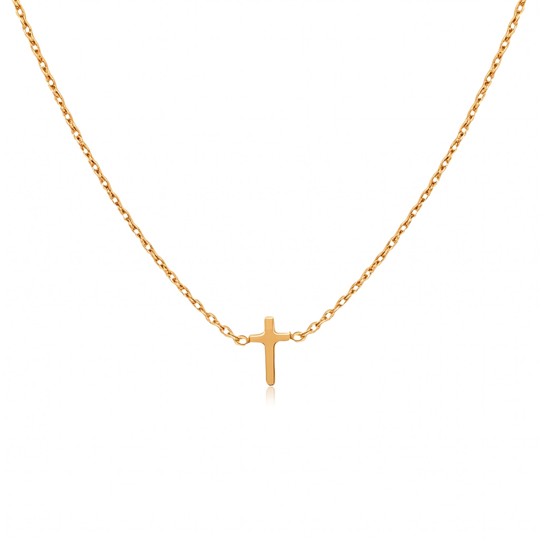 Gold tiny cross necklace laid out on a white background