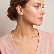 Silver tiny cross necklace worn in a shoulder-forward profile