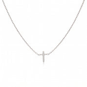 Silver tiny cross necklace laid out on a white background