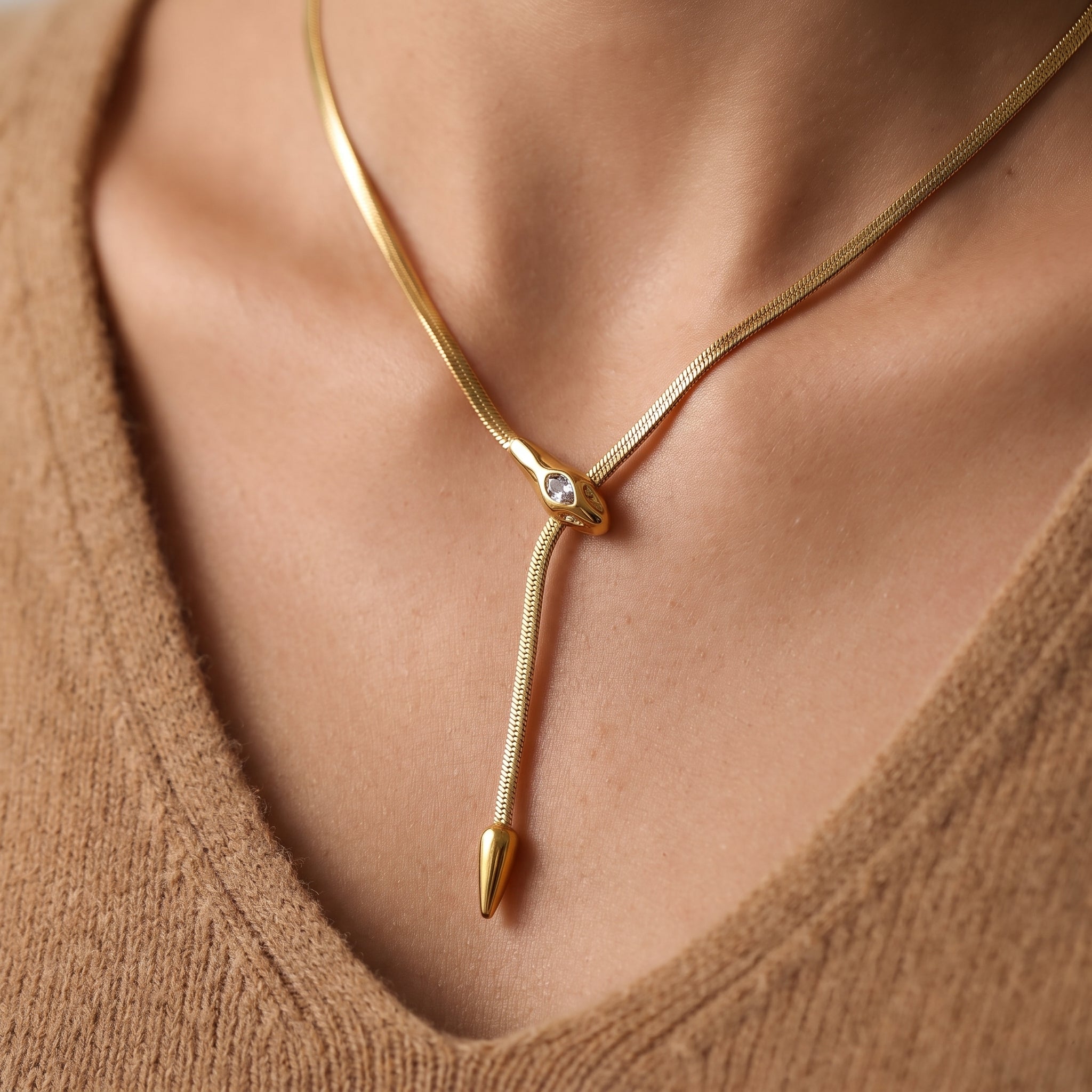 Gold snake necklace with a crystal snake head and lariat drop on skin