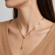 Vesper gold snake lariat necklace, neckline close-up with a camel V-neck sweater