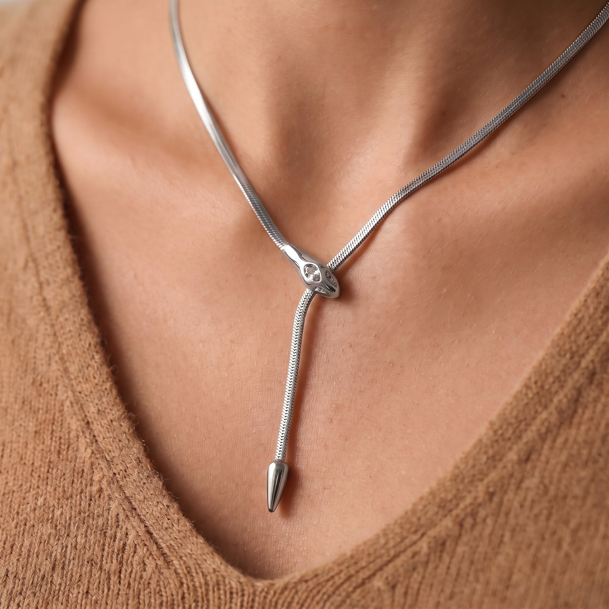 Silver snake necklace with a crystal snake head and lariat drop on skin
