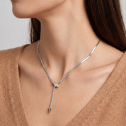 Vesper silver snake lariat necklace, neckline close-up with a camel V-neck sweater