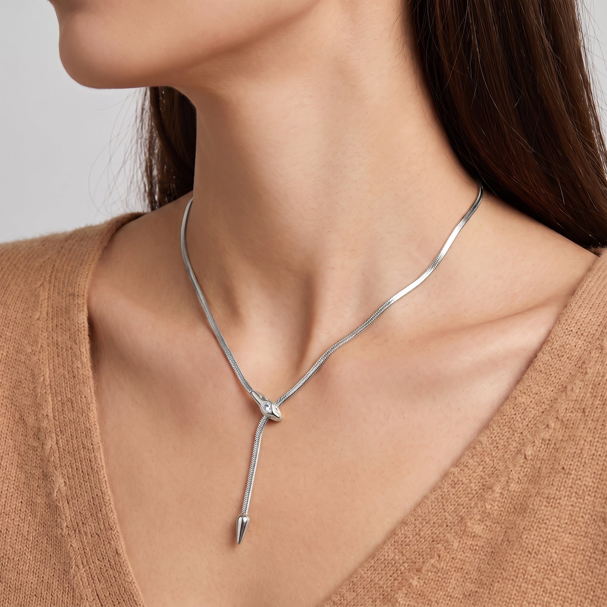 Vesper silver snake lariat necklace, neckline close-up with a camel V-neck sweater