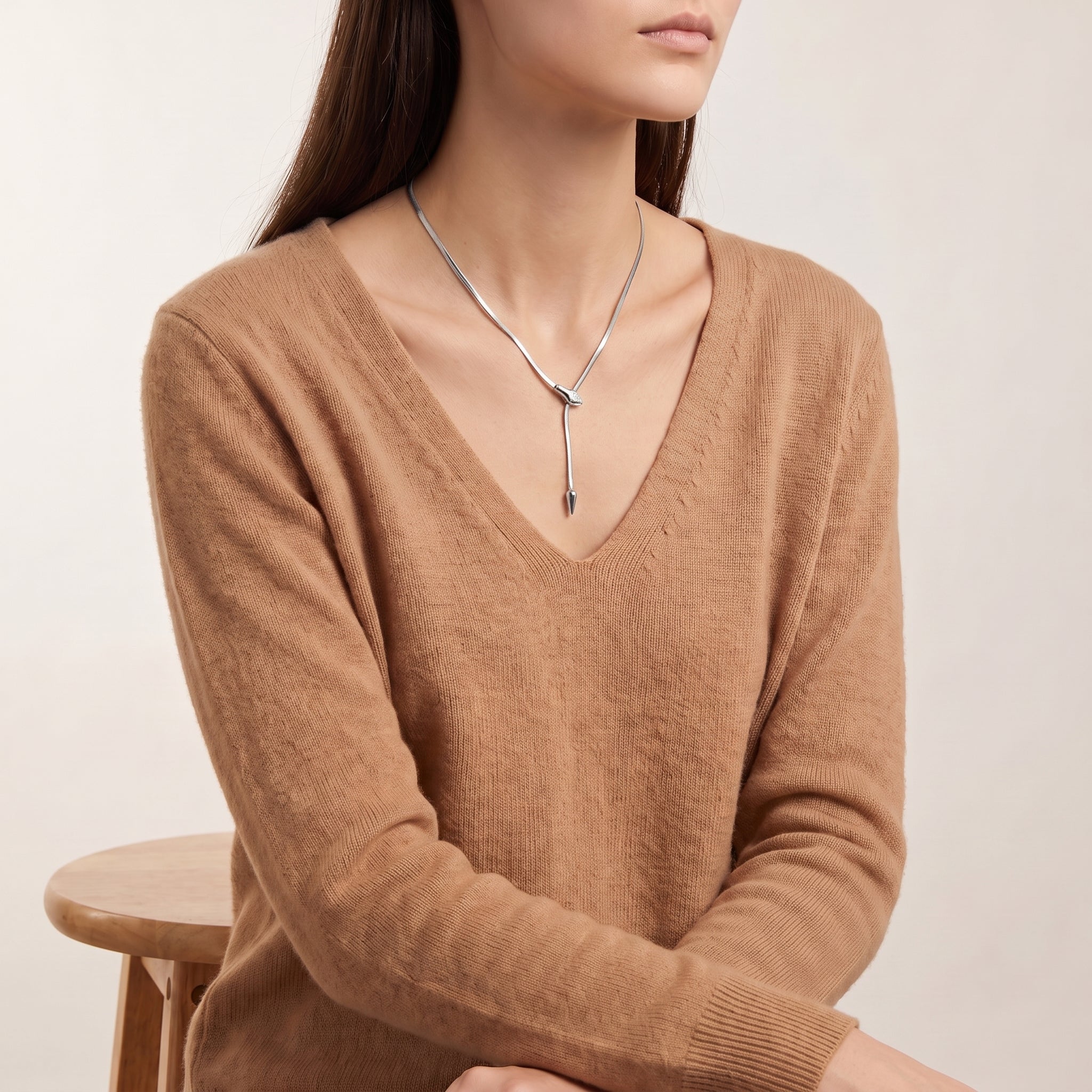 Vesper silver snake lariat necklace, seated portrait in a camel sweater