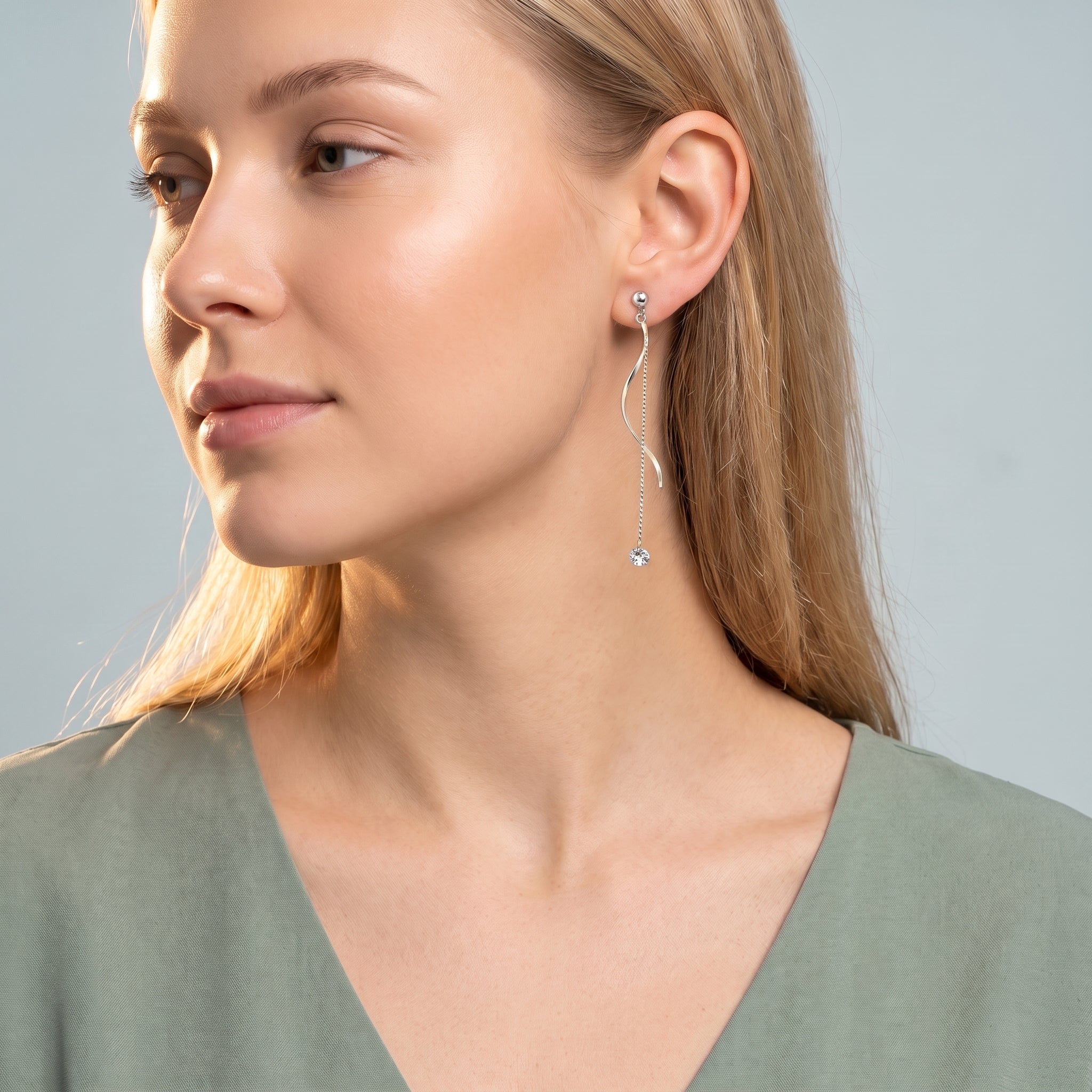 Silver wave drop earring worn with a sage green V-neck top