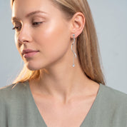 Silver wave drop earring with crystal tip, head turned down