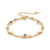 Gold two-chain bracelet with black and white disc stations on white