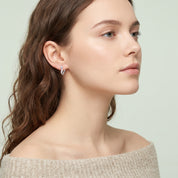Silver frosted huggie earring worn with chin lifted
