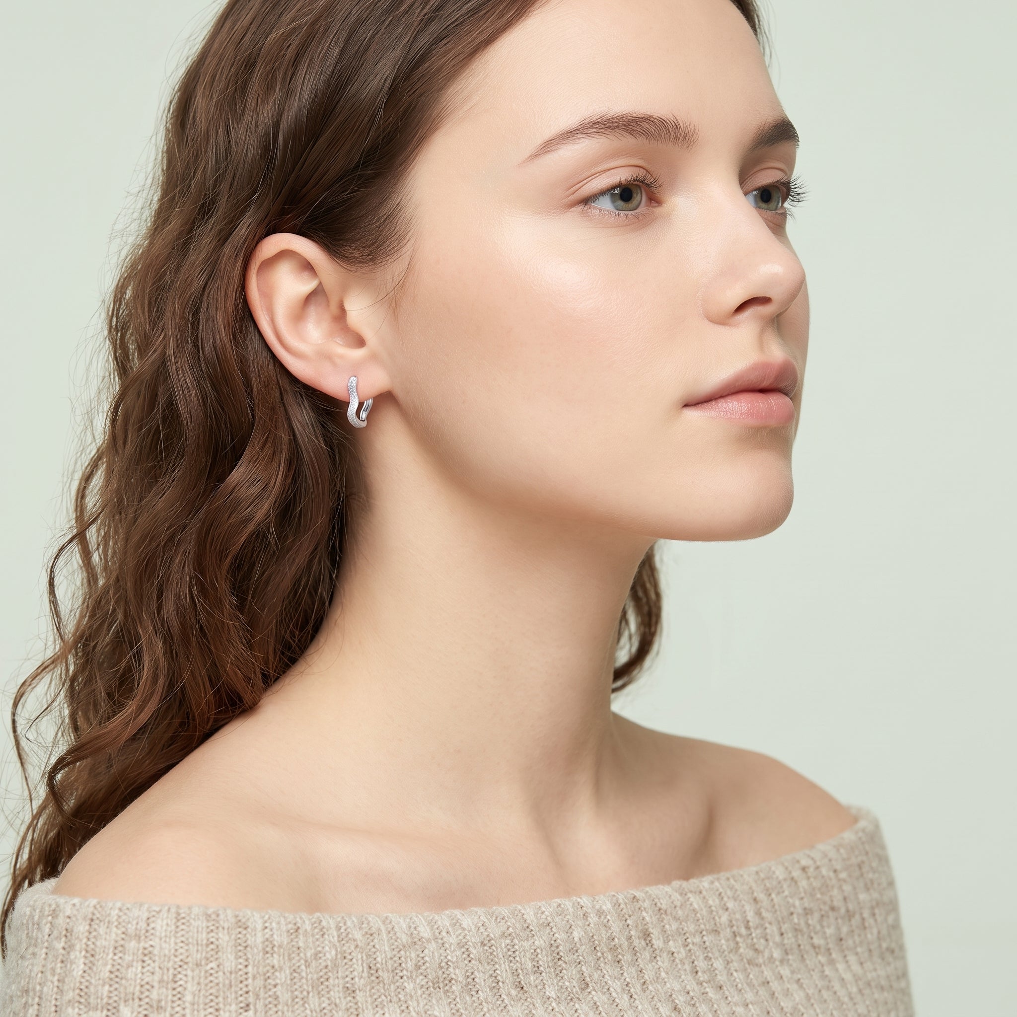 Silver frosted huggie earring worn with chin lifted