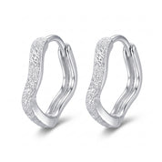 Silver frosted wavy huggie earrings side by side on white